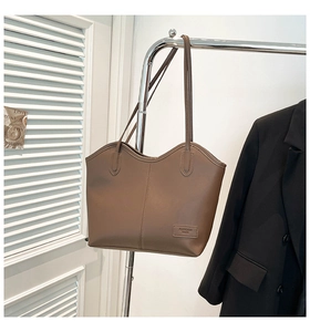Detail of coffee brown faux leather tote bag with vertical stitching and fashion label