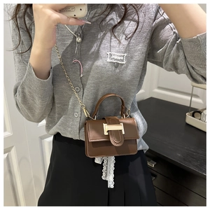 Close-up of brown mini handbag with gold buckle and metal chain strap for women