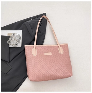 Detailed view of pink woven leather tote bag texture and brand plaque for commute