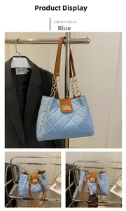 Detail of blue quilted tote bag featuring a brown flap cover and golden twist lock closure