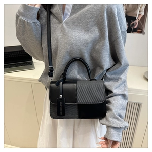 Detail showing mixed texture leather and woven fabric on a stylish crossbody square bag