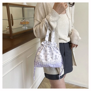 Detail of floral and plaid patchwork bucket bag with delicate lace trim and drawstring closure
