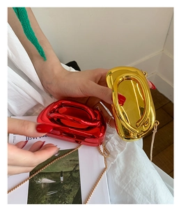 Detailed view of red and gold acrylic clutch bags with metallic ring handles and chains