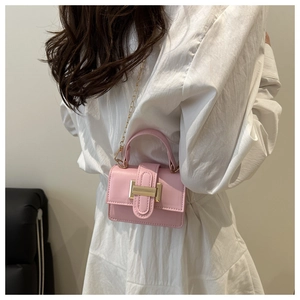 Detailed close-up of pink mini handbag with gold buckle and metal chain strap on model