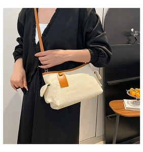 Dettaglio macro della borsa in tela beige con finiture in pelle marrone e piedini in metallo