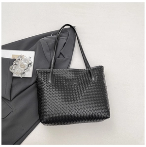 Detail of black woven tote bag with slim shoulder straps and fashion logo emblem