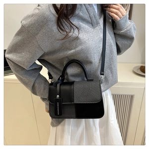 Detail of minimalist color-block square bag with grey woven texture and leather contrast