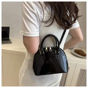 Model view of a vintage black patent shell bag with golden zipper and sleek round handles
