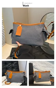 Dettaglio della borsa a spalla in denim con finiture in pelle e tasche laterali