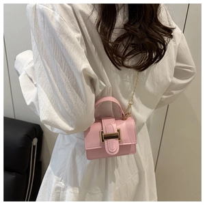 Back view of a pink mini crossbody bag with gold chain strap on a white dress