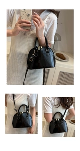 Detail of black glossy patent shell bag with golden zippers and detachable strap