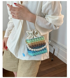 Detail of woven bucket bag with pearl handle, chain strap and drawstring closure