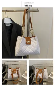 Detail of white quilted tote bag with brown leather strap and gold chain accent