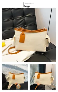 Dettaglio della borsa tote in tessuto beige con finiture e tracolle in pelle marrone su panca