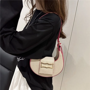 Chic beige woven crescent shoulder bag with pink trim and gold clasp on a model