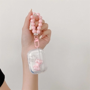 Macro detail of transparent AirPods Pro case with pink bow, white stars and pearl strap