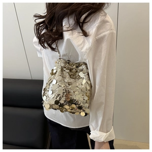 Detail of silver sequined bucket bag with thin metal chain strap on model's shoulder