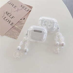 Clear AirPods case with laser bow and elegant pearl butterfly lanyard on a white desk