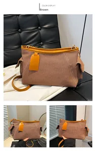 Dettaglio della borsa in tela marrone con finiture in pelle arancione e parti in metallo