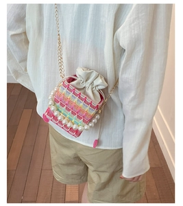 Detail of colorful hand-woven mini bucket bag with pearl handle and golden chain strap
