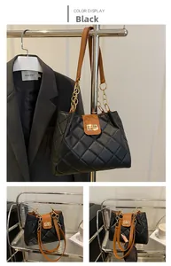 Detail of black quilted shoulder bag featuring golden chain straps and elegant metal clasp