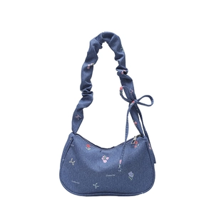Blue denim underarm bag with floral embroidery and scrunchie strap on white background