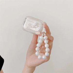 Detailed view of clear AirPods case with white 3D bow and iridescent pearl bead strap