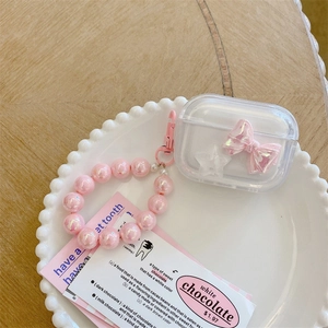 Detailed view of clear AirPods case with pink bow, star pendant and beaded wrist strap