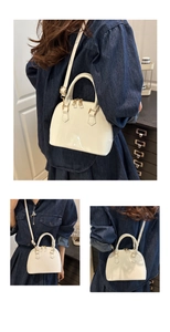 Detailed close-up of cream shell-shaped handbag with glossy finish and gold metal hardware