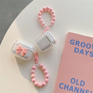 Close-up of clear AirPods case with pink bow decoration and pearly beaded hand strap
