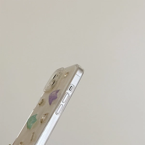 Detail view of transparent phone case with embedded purple petals and silver foil flakes
