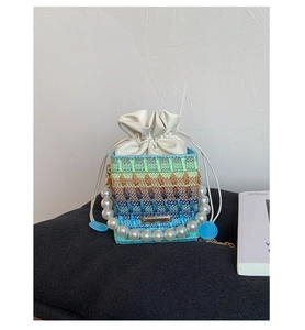 Detailed shot of multi-color woven bucket bag with pearl handle and drawstring closure