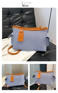 Dettaglio della borsa tote in tela a righe blu con finiture in pelle marrone e tasche laterali