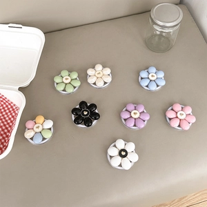 Flat lay of colorful flower-shaped magnetic phone grips with gold heart center accents