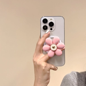 Detail of pink resin flower phone grip with a gold heart center held on a white smartphone