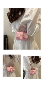 Detail of pink mini square bag with gold H-buckle and chain strap on a white dress