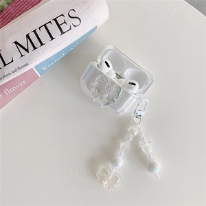 Macro detail of clear AirPods case with iridescent 3D bow and pearl charm strap