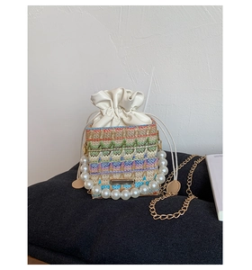 Detail of colorful woven ethnic shoulder bag with pearl handle and golden chain strap
