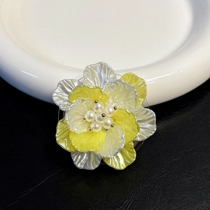 Close-up of a shell flower phone grip with pearl center and yellow-white petals