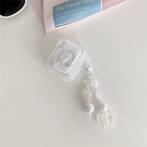 Clear AirPods case with laser-style bow and pearl pendant on a minimal background