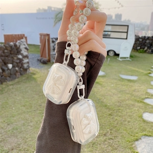 Clear AirPods case with white bow design and iridescent pearl wrist strap in hand