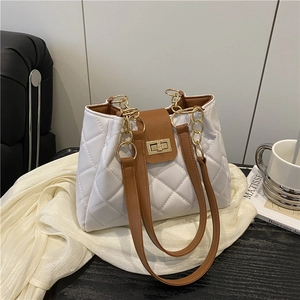 White quilted tote bag with brown leather straps and gold clasp on a wooden table