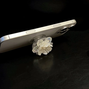 3D shell flower magnetic phone socket with pearl center on black leather background