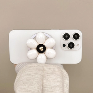 Detail of a white flower phone grip with a small gold heart on a neutral background