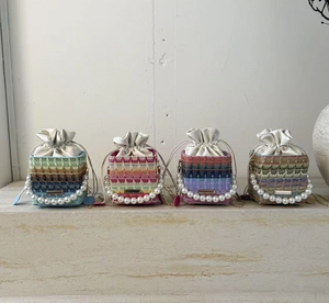 Detailed knit texture of colorful woven bucket bags with large pearl handles and drawstrings