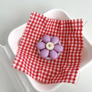 Close-up of purple flower magnetic phone socket with golden heart on picnic background