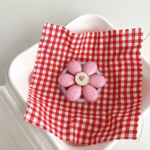 Close-up of pink flower magnetic phone holder with a gold heart center on checkered cloth