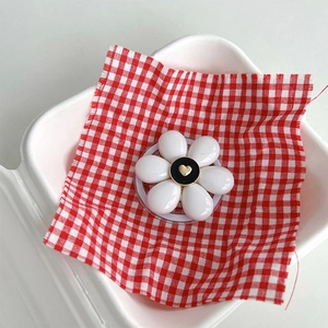 Detail of floral magnetic phone socket with gold heart on white petals and black center