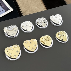 Elegant heart-shaped phone grip with metal bow and star details in gold and silver