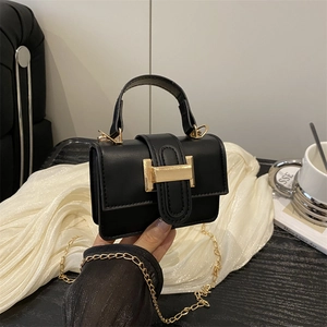 Mini black square handbag with gold H buckle and chain strap on minimalist background